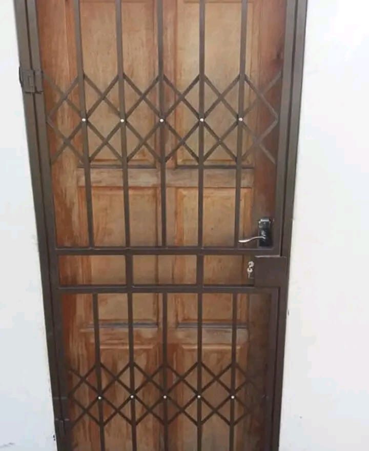 Ornate diamond-pattern burglar guard fitted over a timber front door