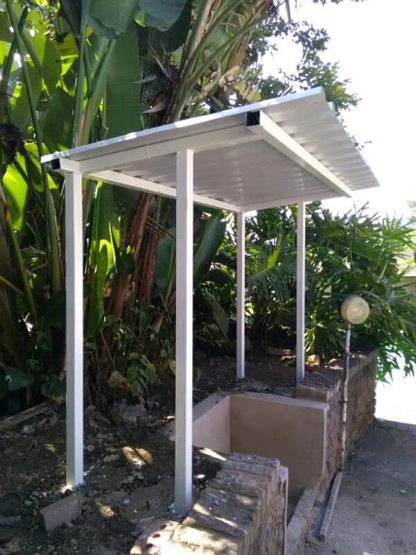 Freestanding steel carport structure built into a garden setting