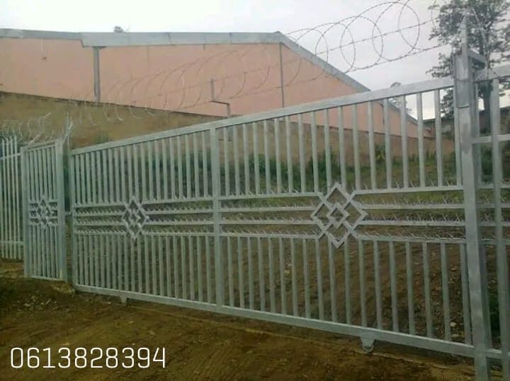 Steel gate with palisade fencing and a razor-wire coil for extra security