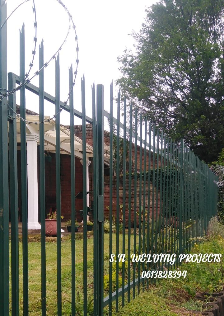 Palisade fencing topped with a razor-wire coil for extra security