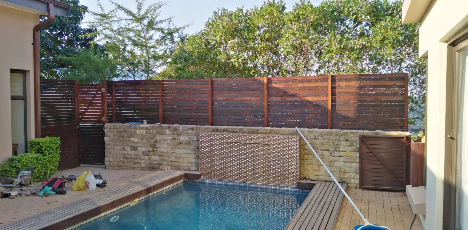 Timber-slat privacy screening bordering a pool area