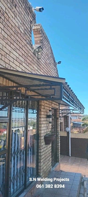 Completed steel window canopy and burglar guards on a brick home